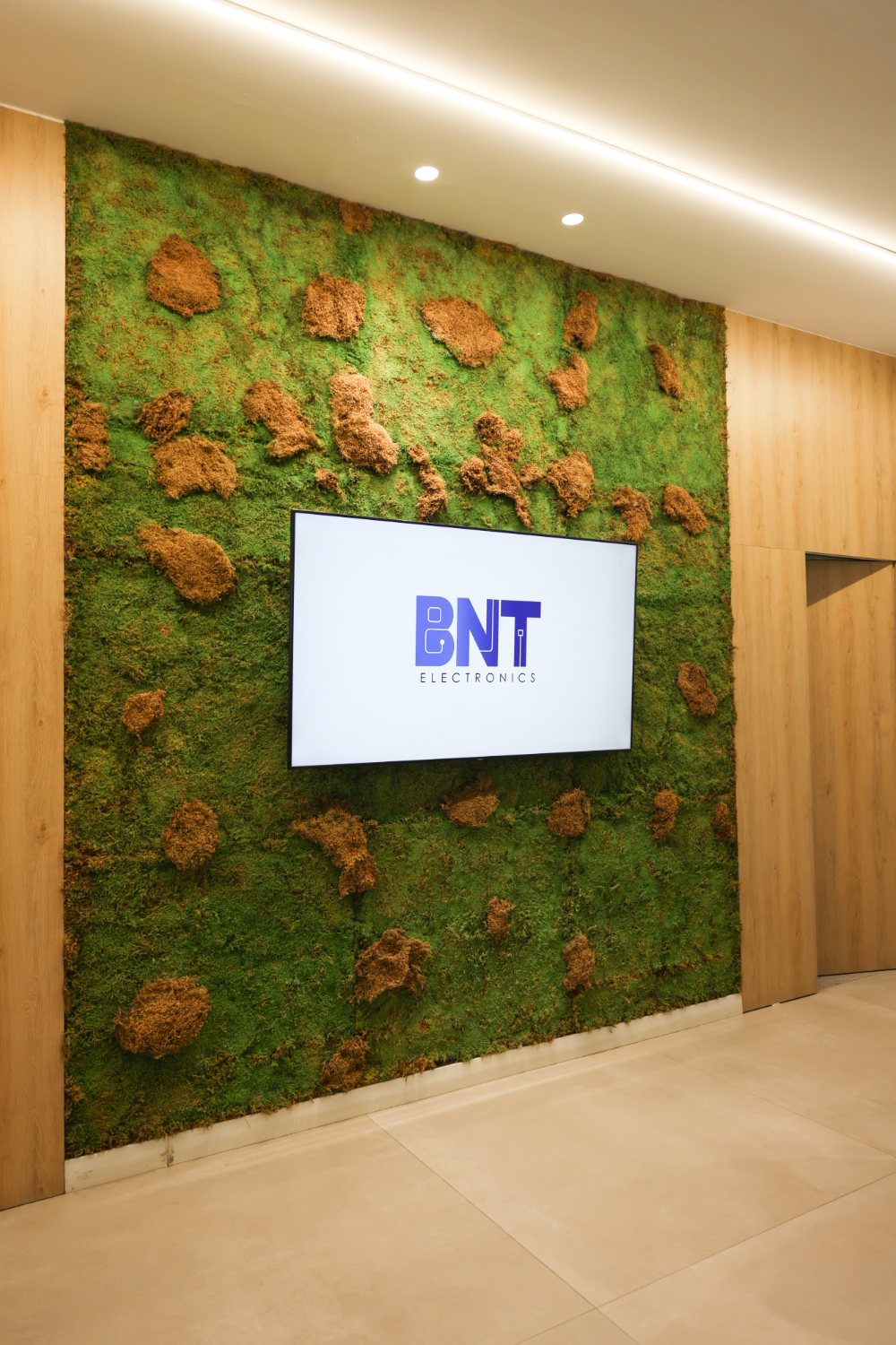 The moss wall and BNT Electronics sign in the reception of the Tirana office