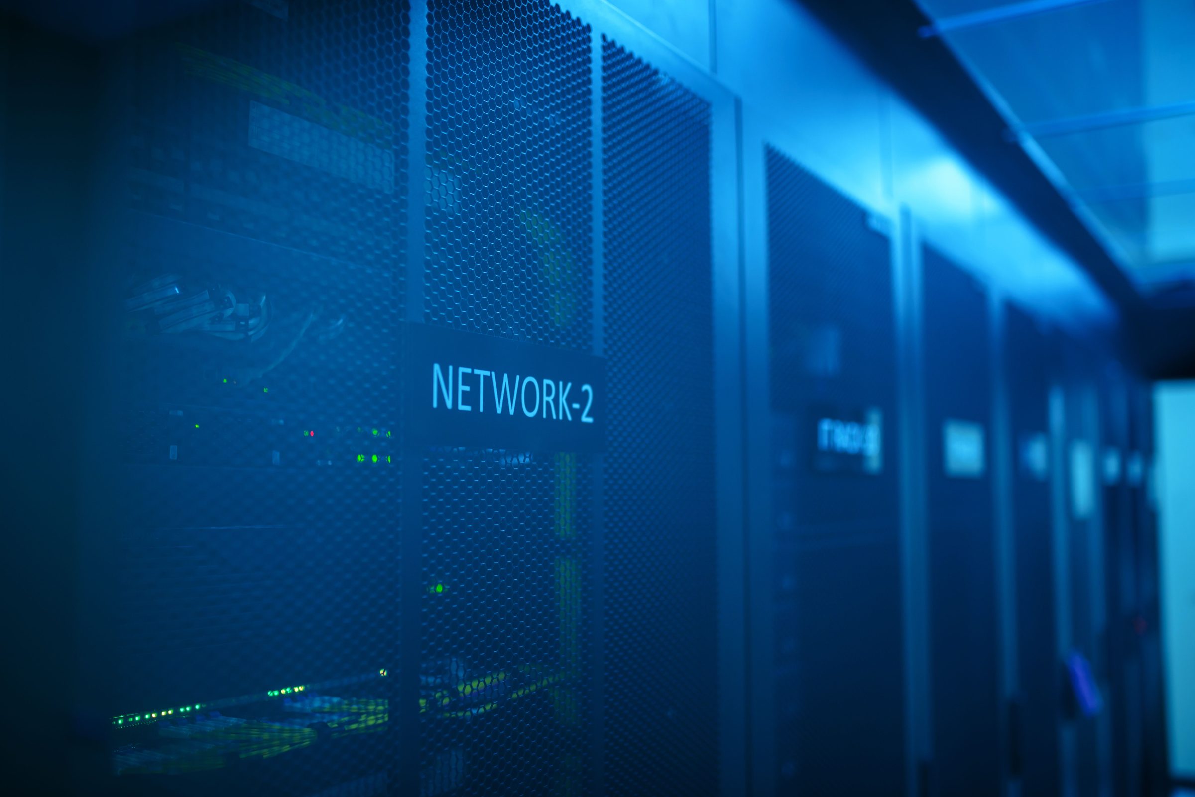 Rows of network racks in a data centre, lit in blue.